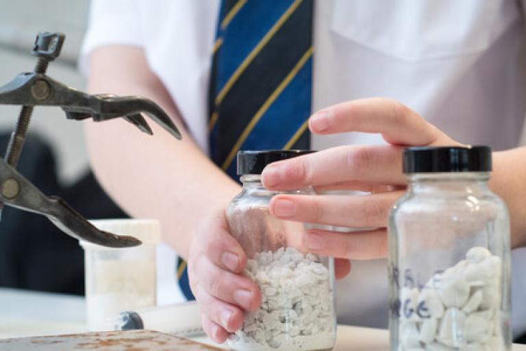 School pupil opening jar in science lesson
