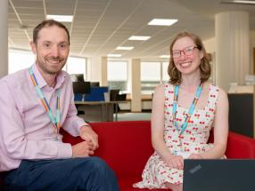 Coworkers sitting on a red sofa smiling