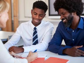 A father and teenage child talking to a teacher